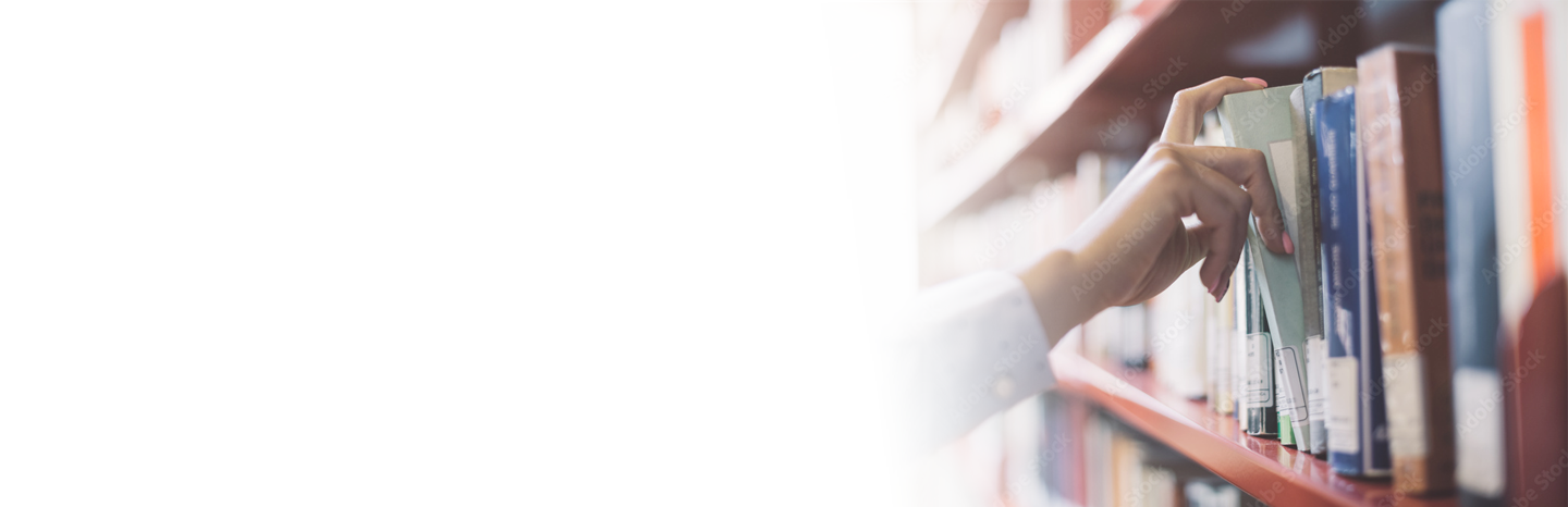 Student pulling a book off a shelf in a college library
